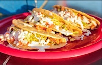 three tacos are sitting on a pink plate